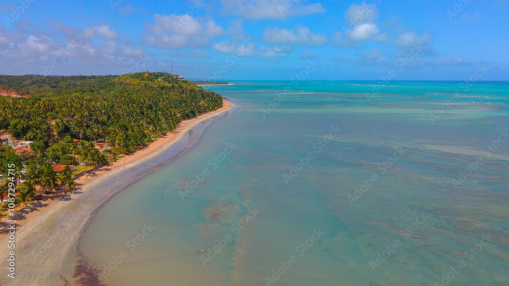 Aerial view of Jarapatinga Beach, Alagoas, with calm green and blue waters, golden sand, and surrounded by lush vegetation, creating a paradisiacal seaside retreat in Alagoas, Brazil. Aerial view of Jarapatinga Beach, Alagoas, with calm green and blue waters, golden sand, and surrounded by lush vegetation, creating a paradisiacal seaside retreat in Alagoas, Brazil.