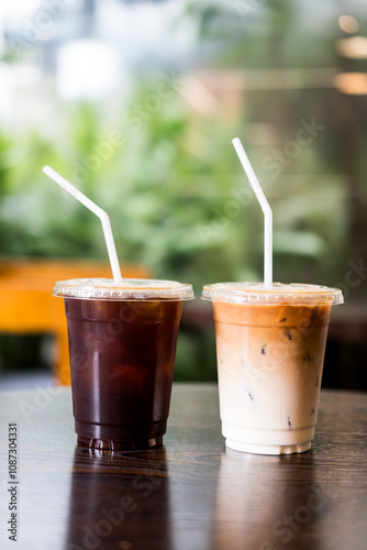 Take away cup of iced latte coffee and iced black coffee against nature background