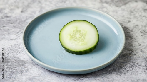 A baby blue plate with a single cucumber slice, simple food photography, pastel color tones, high resolution photo