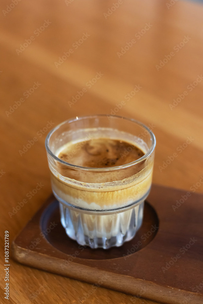 Dirty coffee on a wooden table; layered drink with a distinct robust espresso layer on the top and chilled cold milk or cream at the bottom. Dirty coffee on a wooden table; layered drink with a distinct robust espresso layer on the top and chilled cold milk or cream at the bottom.