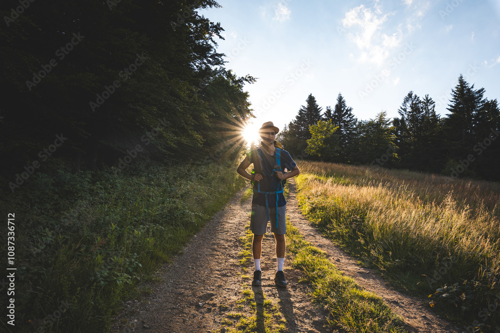Hiker with backpack standing on a sunlit trail in the Beskydy Mountains, Czech Republic. Embracing adventure and nature, surrounded by forests and open meadows at sunset Hiker with backpack standing on a sunlit trail in the Beskydy Mountains, Czech Republic. Embracing adventure and nature, surrounded by forests and open meadows at sunset