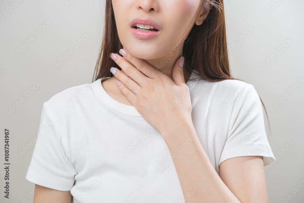 Sickness in inflaming asian young woman, girl use hand check self touch at sore throat, pain thyroid gland on neck or disease reflux, acid of suffer people on wall background. Medical and healthcare. Sickness in inflaming asian young woman, girl use hand check self touch at sore throat, pain thyroid gland on neck or disease reflux, acid of suffer people on wall background. Medical and healthcare.