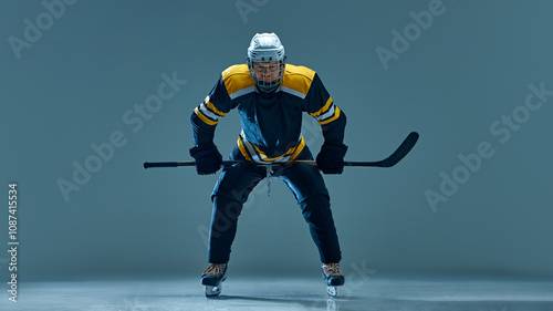 Photography Man, ice hockey athlete in black and yellow uniform during powerful game on ice, captured in athletic stance against studio background