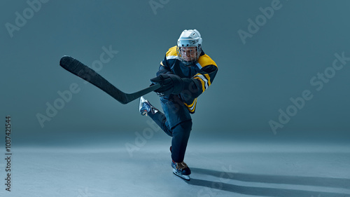 Photography Focused man, ice hockey player captured in motion, powerfully skating across rink, holding stick