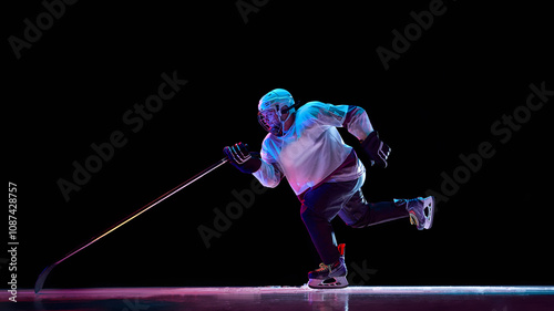 Photography Side view dynamic image of man, hockey player in motion with stick, training, playing intense game against black studio background in neon light