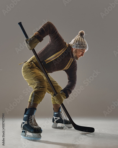 Photography Man, hockey player in knitwear, hat, sweater, pants with suspenders in motion with stick, showing focus and skills