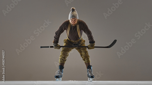 Canvas Print Focused, competitive man in vintage clothes, sweater, hat and pants with suspenders, playing hockey, showing skills