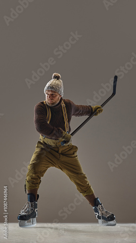 Photography Focused, competitive man in vintage clothes, sweater, hat and pants with suspenders, playing hockey, showing skills