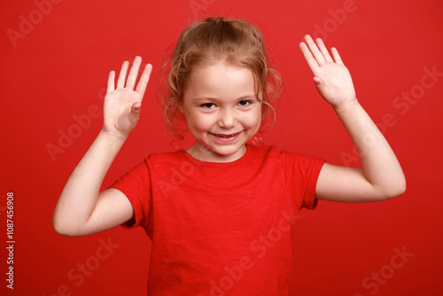 Beautiful blonde little girl, isolated on red studio background