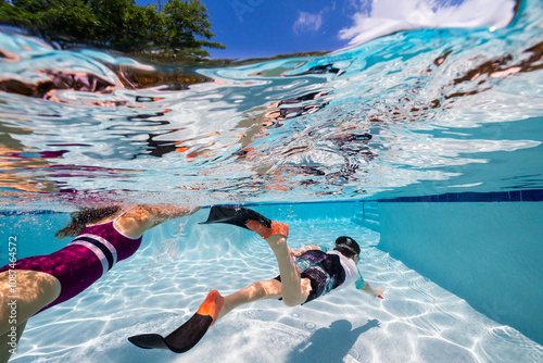 Woman with her kids swimming underwater in a pool