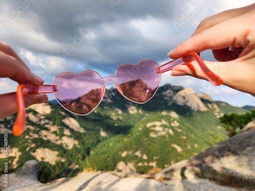 Rose-Colored Sunglasses in the shape of a heart close-up with mountains in the background. concept of seeing the world differently. weather forecast. protection from solar radiation