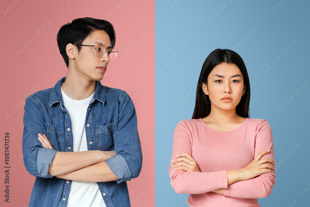 Asian young man looking with sorrow at his angry girlfriend, couple fight over grey background