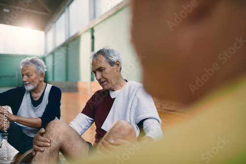 Senior men taking a break from playing basketball in an indoor gym