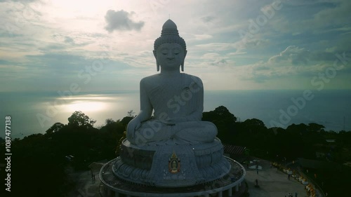 Silhouette of Maravija Big Buddha of Phuket high statue on mountain against cloudy sky and ocean aerial view. Buddhist temple for tourists and locals at sunrise. Asian religion tradition photo