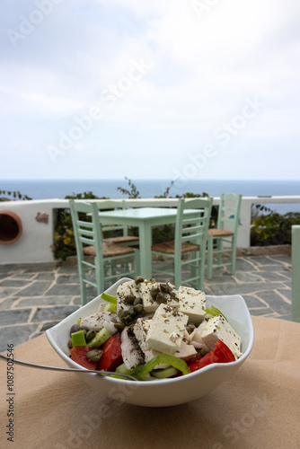 Obraz na płótnie Delicious farmers salad called Horiatiki and a table in front of the blue Aegean sea during summer time as greek food concept.
w salonie