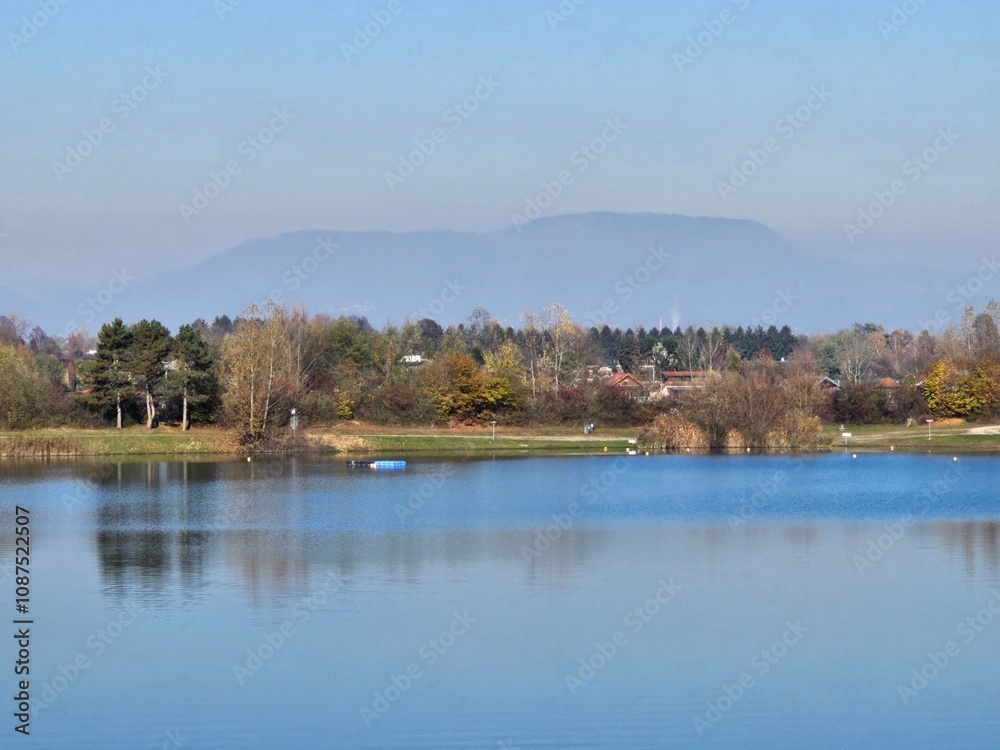 Wunderschöne Spiegelung von Böschung, Bäumen und Rasen in See im Herbst