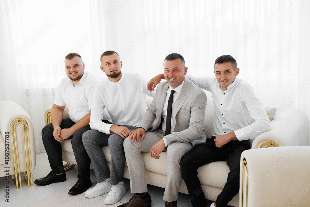 A group of men are sitting on a couch, one of them wearing a tie. Scene is relaxed and comfortable, as the men are sitting close together and enjoying each other's company A group of men are sitting on a couch, one of them wearing a tie. Scene is relaxed and comfortable, as the men are sitting close together and enjoying each other's company