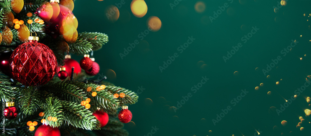 Obraz premium Decorated xmas spruce tree with Christmas red ornaments on green background with lights. Merry Christmas card. Winter holiday festive theme. Happy New Year. 