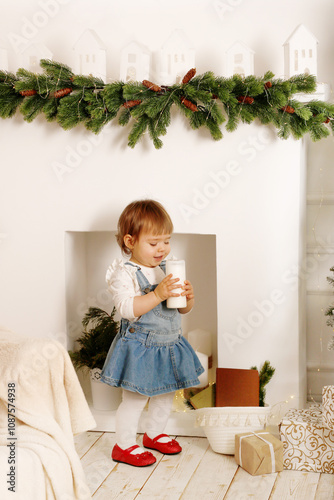 little girl in a room with Christmas decor holding a candle