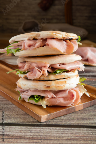 Tigelle with mortadella and rocket on wooden cutting board