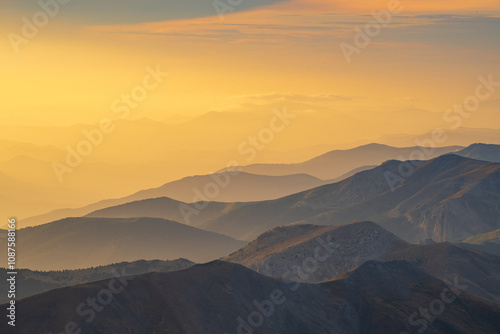 Atardecer desde la montaña con relieves de cimas y sol