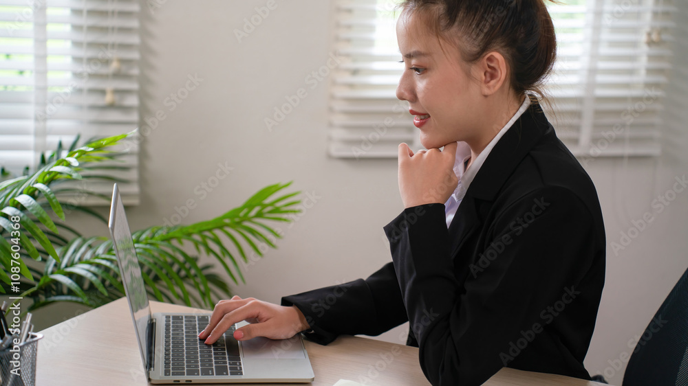 Businesswoman sitting at desk on couch in workplace or at home working on laptop and analyzing data on charts and graphs and writing on papers to make business plan Businesswoman sitting at desk on couch in workplace or at home working on laptop and analyzing data on charts and graphs and writing on papers to make business plan