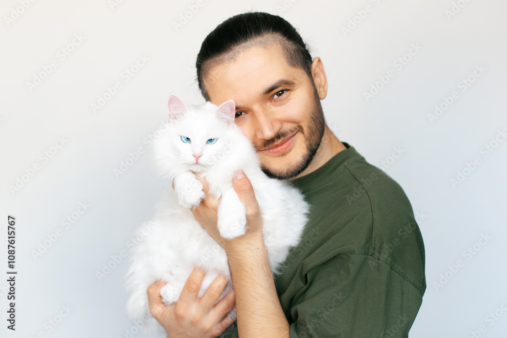 Portrait of young smiling man with white Maine Coon cat in hands on white background. Portrait of young smiling man with white Maine Coon cat in hands on white background.