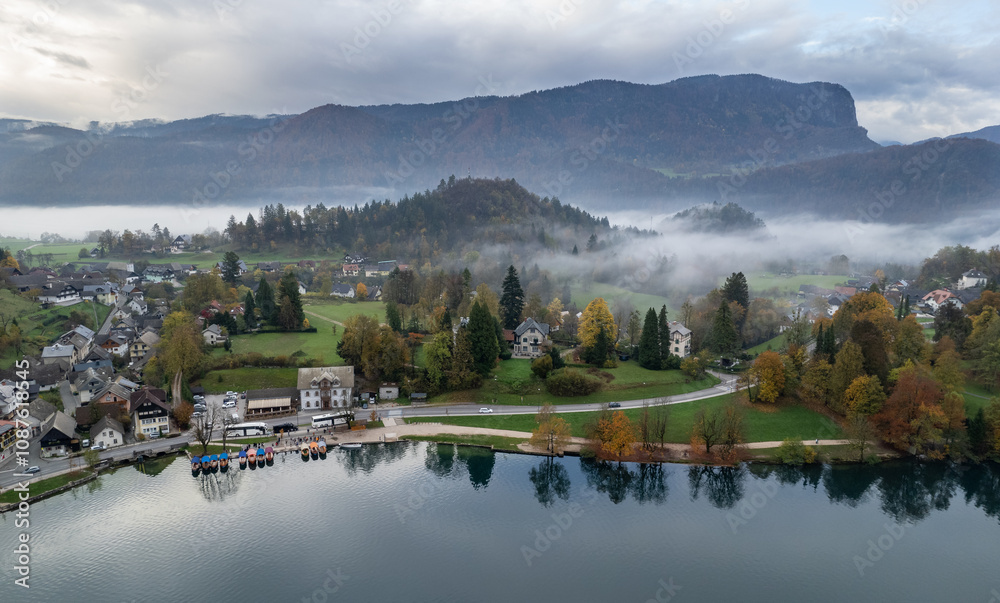 Fototapeta premium Lake Bled valley embraced by fog during fall foliage season