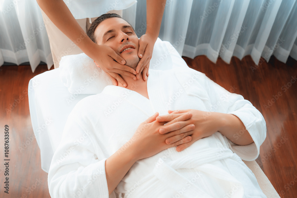 Caucasian man enjoying relaxing anti-stress head massage and pampering facial beauty skin recreation leisure in dayspa modern light ambient at luxury resort or hotel spa salon. Quiescent Caucasian man enjoying relaxing anti-stress head massage and pampering facial beauty skin recreation leisure in dayspa modern light ambient at luxury resort or hotel spa salon. Quiescent