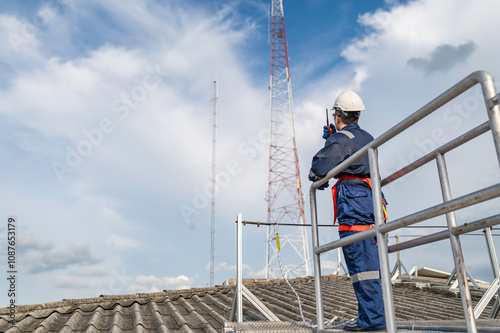 Engineer in Full Safety Gear Climbing a Ladder to Inspect Communication Signals and Industrial Machinery at a High-Risk Transportation Facility