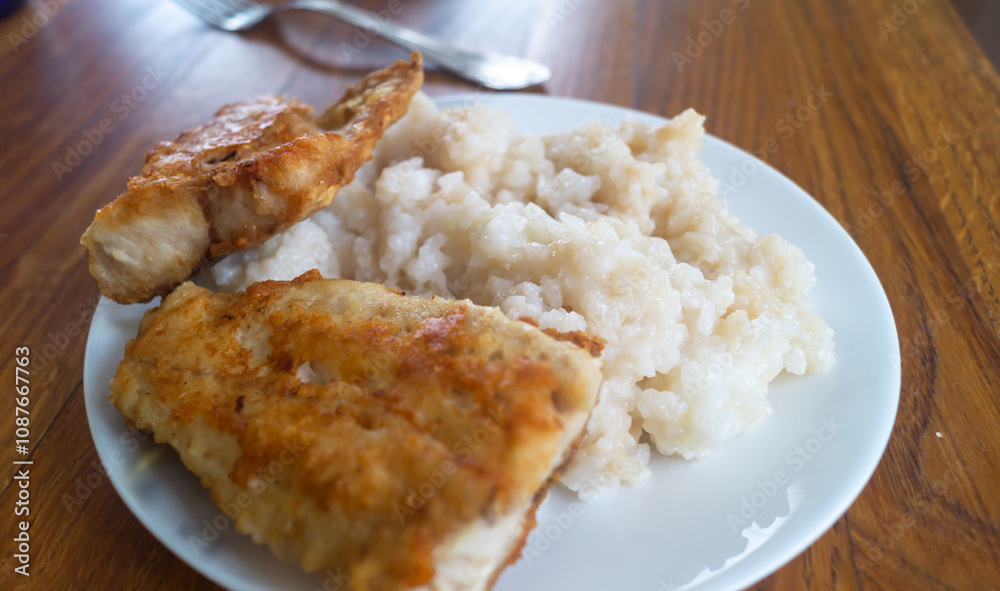 Fried fish and rice and plates on wooden table close-up Fried fish and rice and plates on wooden table close-up