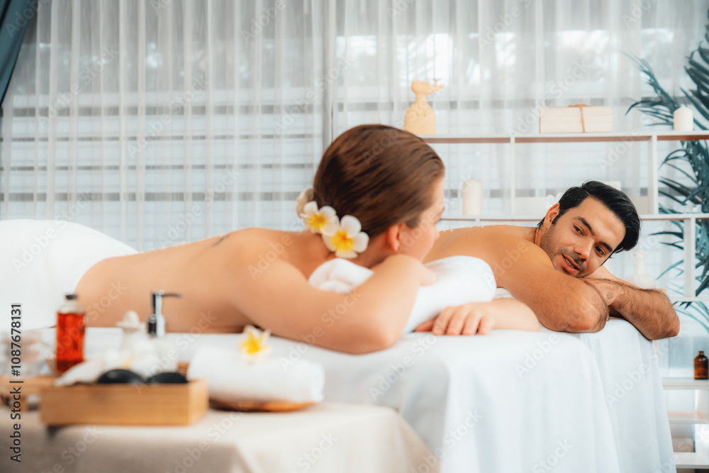 Blissful couple customer having exfoliation treatment in luxury spa salon with warmth candle light ambient. Salt scrub beauty treatment in health spa body scrub. Quiescent Blissful couple customer having exfoliation treatment in luxury spa salon with warmth candle light ambient. Salt scrub beauty treatment in health spa body scrub. Quiescent