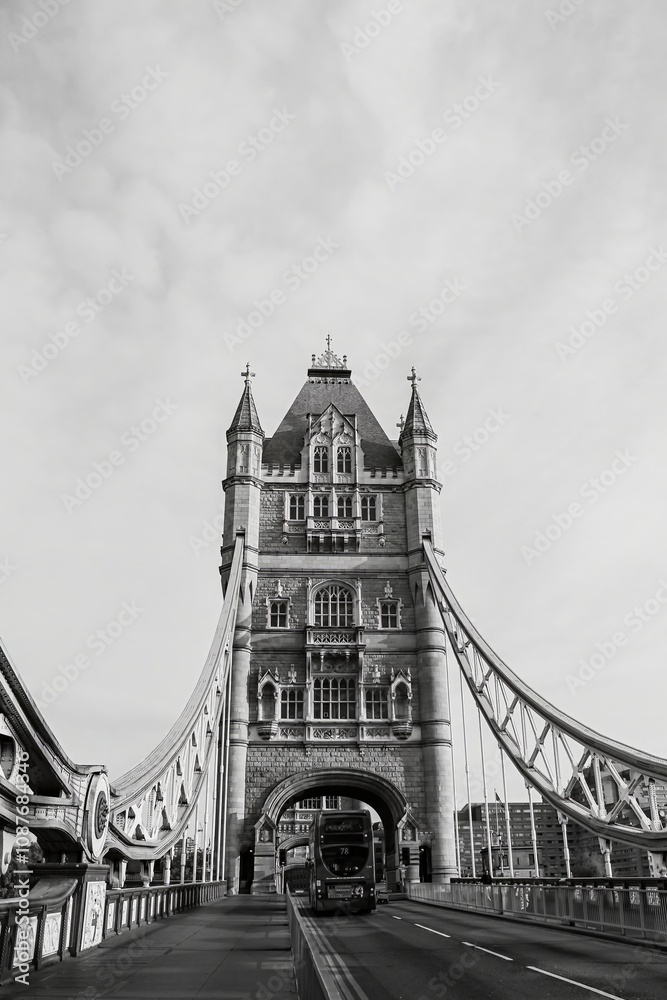 Obraz premium A stunning black and white shot of the Tower Bridge in London with a bus crossing beneath its iconic towers.