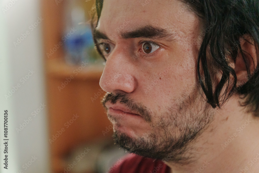 Obraz premium A close-up of a man with tousled hair, revealing his curious expression in a vibrant, colorful setting during a lively gathering