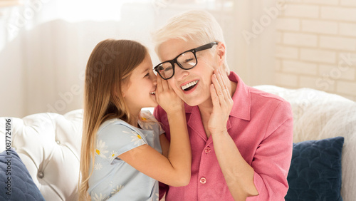 Family bonding. Little girl sharing secrets with her granny at home