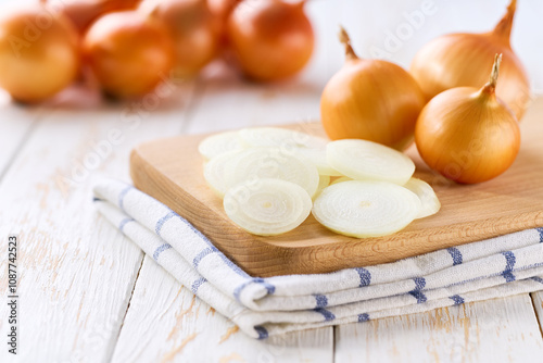 Sliced yellow onions in a cutting board on a light kitchen table.