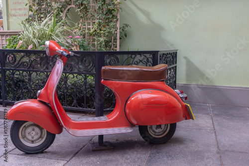 vintage red scooter with brown leather seat in courtyard