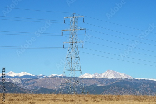 Overhead power lines with blue sky and snowy mountains in the background