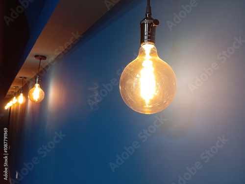Electric light bulbs with yellow light on a dark wall background hang in a dark room