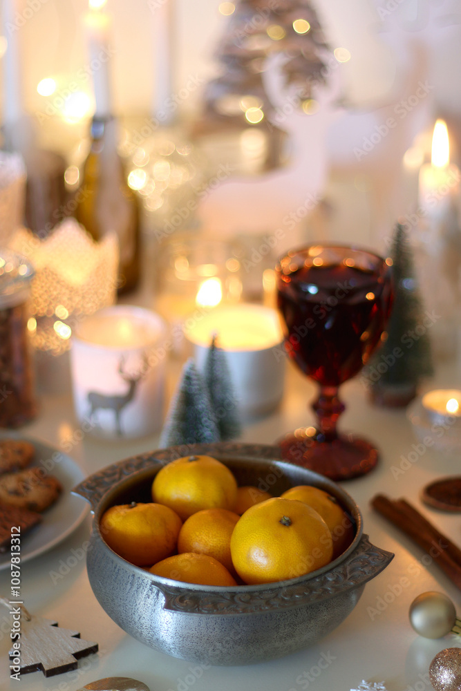 Various Christmas decorations, cookies, chocolate, nuts and tangerines, wine glasses and lit candles on the table. Holiday hygge at home. Selective focus. Various Christmas decorations, cookies, chocolate, nuts and tangerines, wine glasses and lit candles on the table. Holiday hygge at home. Selective focus.