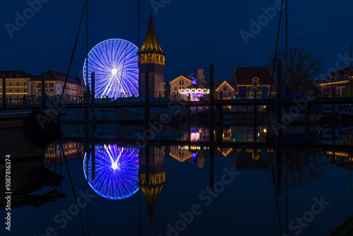 Nachtaufnahme eines Jahrmarktes mit großem Riesenrad am Hafen.