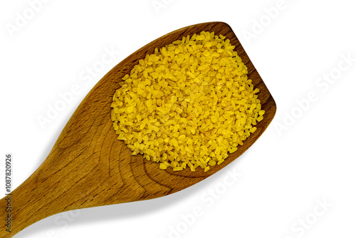 Wooden spoon resting on white background containing bulgur wheat.