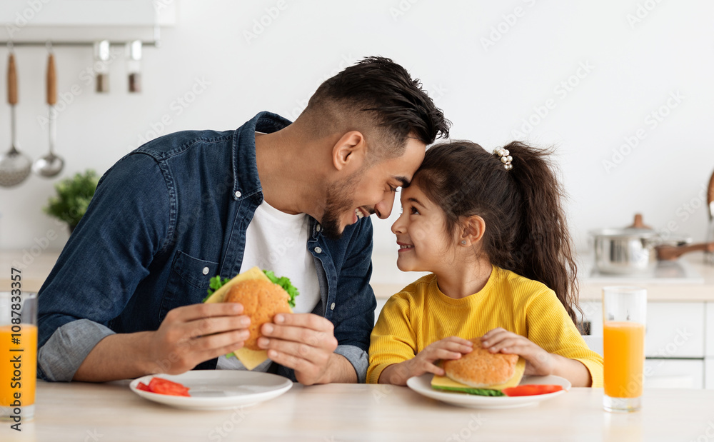 Happy Loving Arab Dad And Daughter Eating Sandwiches In Kitchen And Bonding, Cheerful Middle Eastern Father And Cute Little Female Child Touching Foreheads And Smiling, Enjoying Time Together Happy Loving Arab Dad And Daughter Eating Sandwiches In Kitchen And Bonding, Cheerful Middle Eastern Father And Cute Little Female Child Touching Foreheads And Smiling, Enjoying Time Together