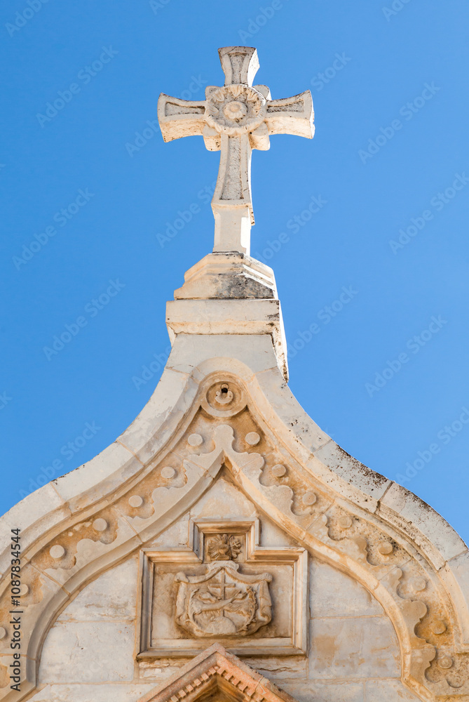 An Architectural Cross Situated on a Majestic Historical Building Under a Clear Blue Sky An Architectural Cross Situated on a Majestic Historical Building Under a Clear Blue Sky