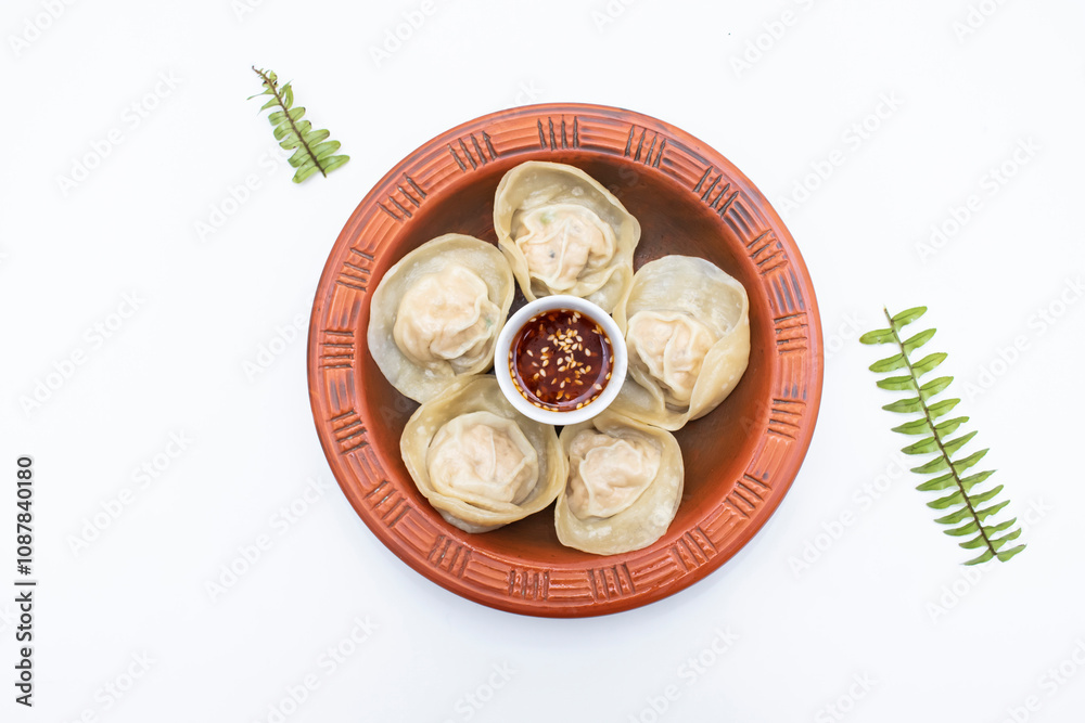Chicken momo dumplings dim sum with spicy sauce served in clay pot isolated on white background top view of indian, pakistani and bangladeshi food Chicken momo dumplings dim sum with spicy sauce served in clay pot isolated on white background top view of indian, pakistani and bangladeshi food