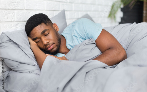 Just resting. Young african-american man sleeping in bed at home, having good dreams, copy space