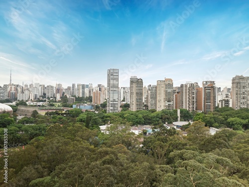 Fototapeta Naklejka Na Ścianę i Meble -  Vista aérea do Parque Ibirapuera em São Paulo, e o skyline da cidade ao fundo. Cenário urbano com áreas verdes, céu azul.
