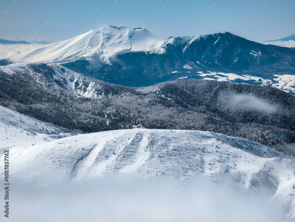 Fototapeta premium Towering snow covered volcano above a layer of cloud (Mount Asama)