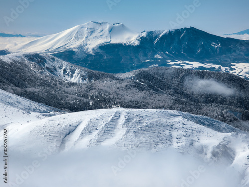 Towering snow covered volcano above a layer of cloud (Mount Asama) photo