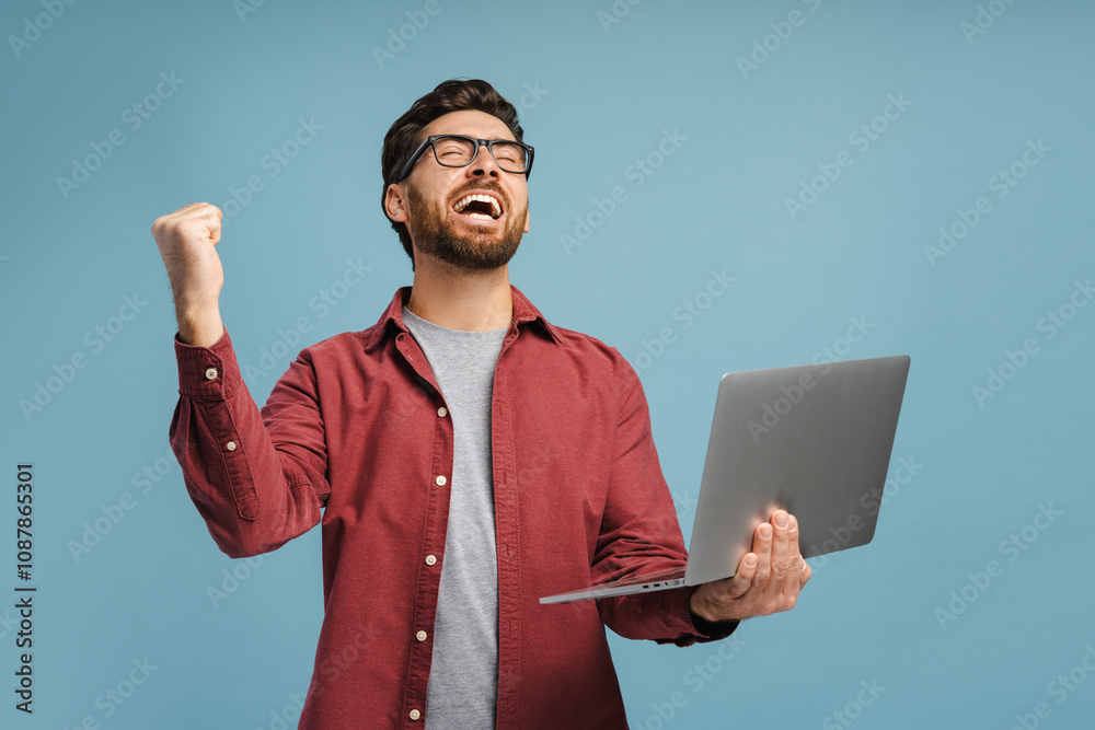 Portrait of happy, amazed bearded man wearing eyeglasses, holding laptop, using computer Portrait of happy, amazed bearded man wearing eyeglasses, holding laptop, using computer